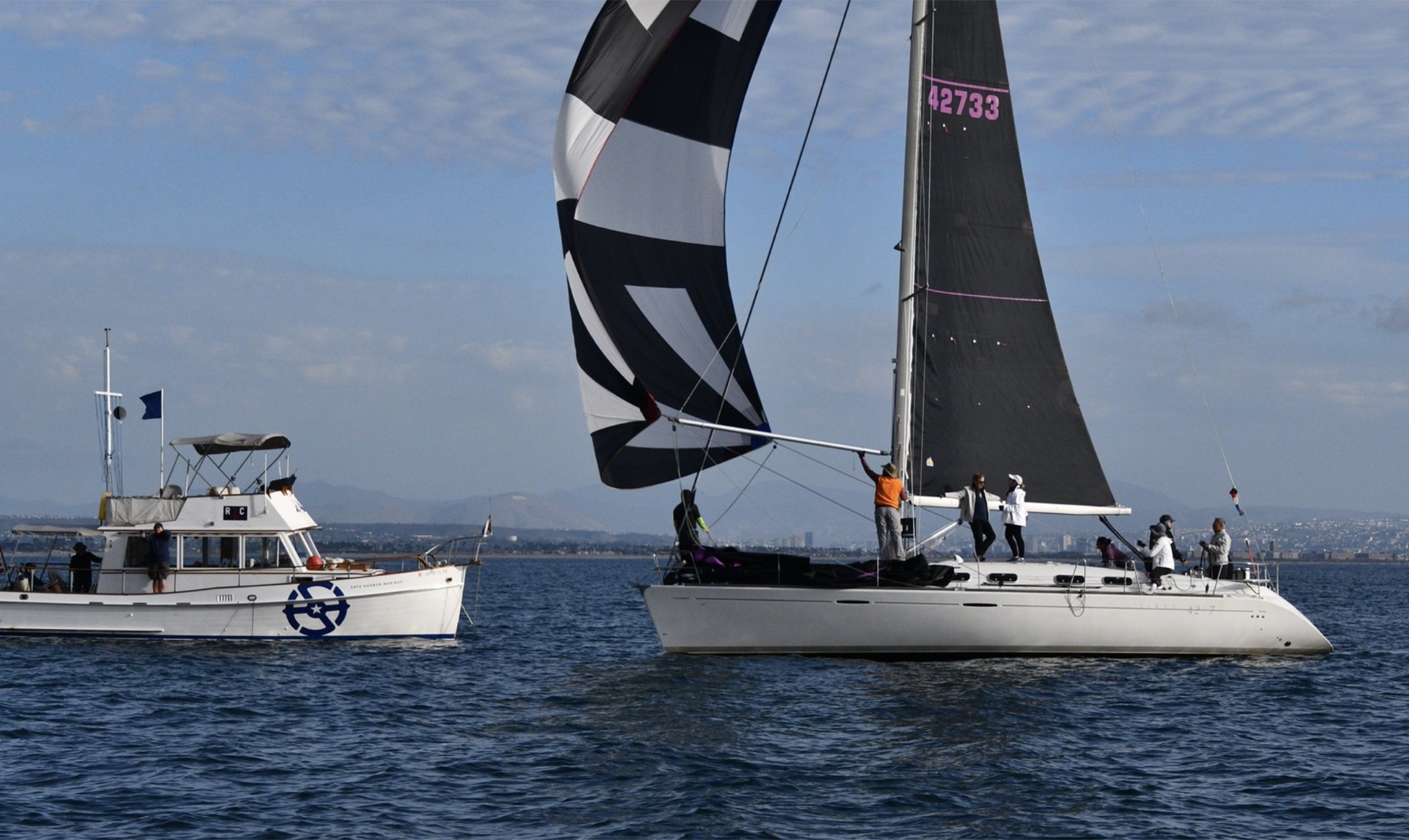 Modern racing sailboat #42733 flying black-and-white spinnaker near race committee boat