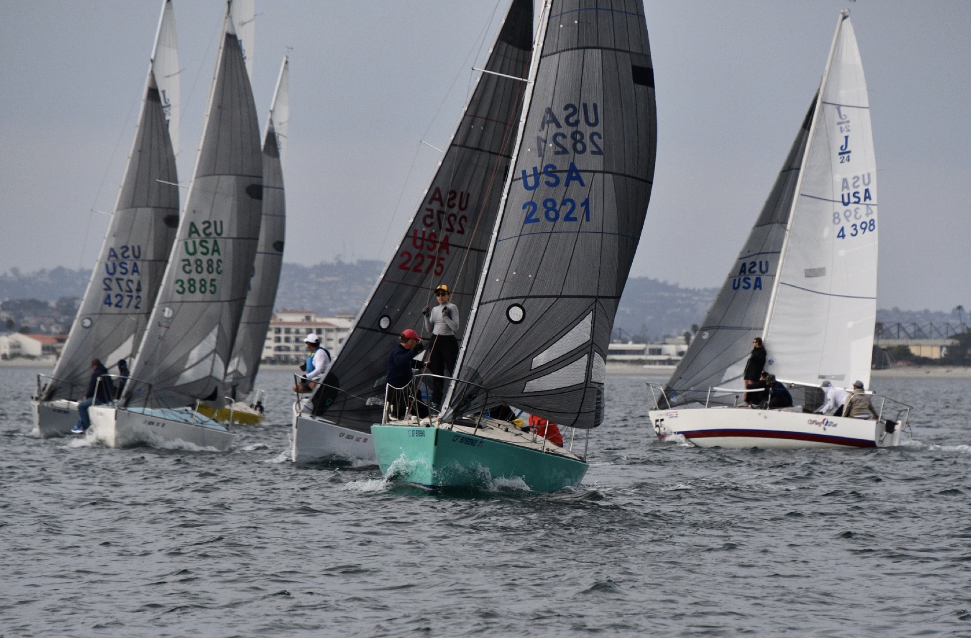 Close-quarters Corinthian one-design regatta racing with turquoise hull in foreground